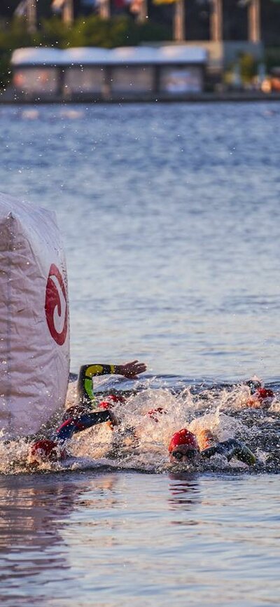 Swimmers swimming around course buoy