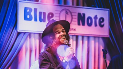 Man singing in front of a Blue Note sign