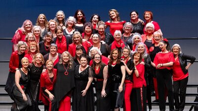 A group shot of a choir. They are dressed in red and black clothes.