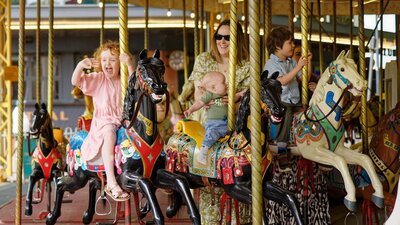 A group of children and an adult riding the merry-go-round