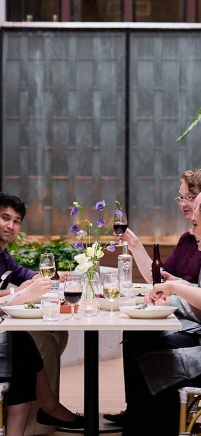 Guests raising their wine glasses in a celebratory toast around a Christmas lunch table.