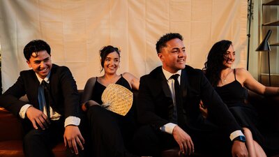 The Amosa family sitting and smiling dressed in formal wear and posed for a photo shoot