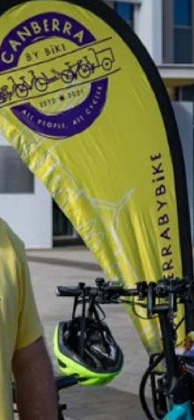 Man in yellow and purple branded t-shirt standing in front of yellow flag