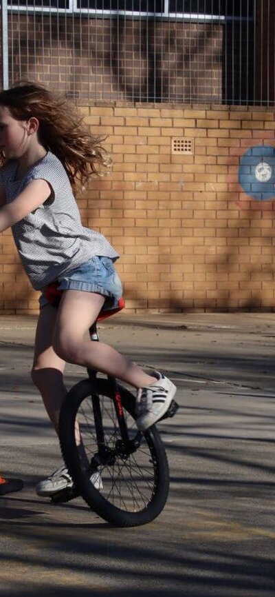 A girl is speeding around a unicycle obstacle course