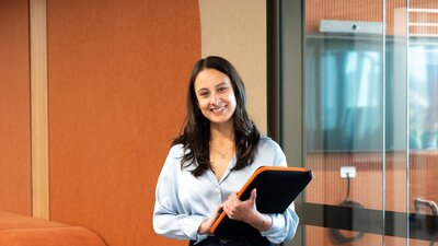 woman smiling at camera holding a folder in an office