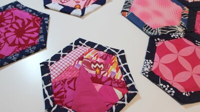 Pink patterned fabric is surrounded by blue fabric to create a hexagon