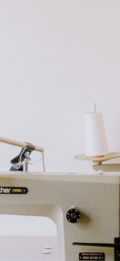 A pale white sewing table sits in front of a white wall.