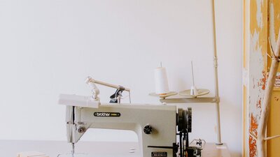 A pale white sewing table sits in front of a white wall.