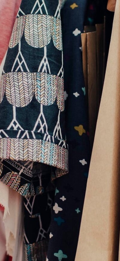 A close-up of clothes hanging on a rack. They are all different patterns and colours