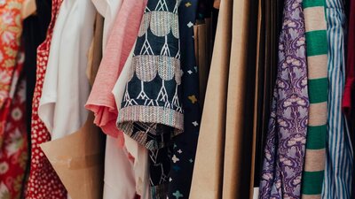 A close-up of clothes hanging on a rack. They are all different patterns and colours