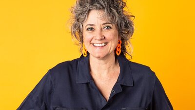 middle aged women wearing blue jumpsuit on bright yellow background
