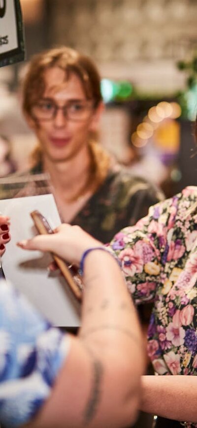 person in a blue shirt buying items from an artists table