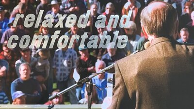 A press photo of John Howard giving a public speech with 'relaxed and comfortable' to the left