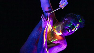 Man painting his arm with UV body paint