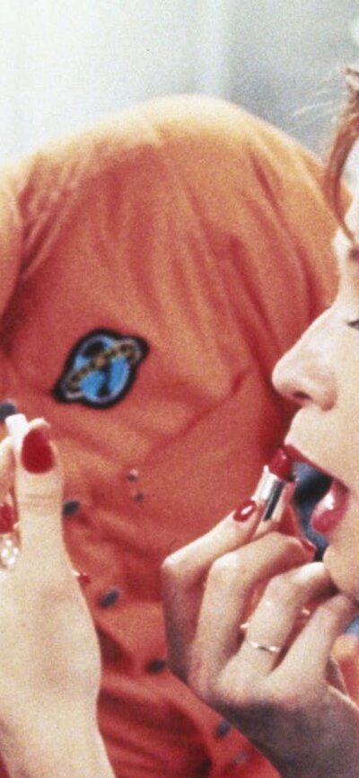 man watching a woman apply lipstick