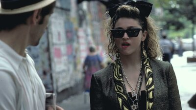 Desperately Seeking Susan, Fri 17 Apr 8:00 PM Woman walking towards man wearing 1980s style clothing, sunnies and big hair bow