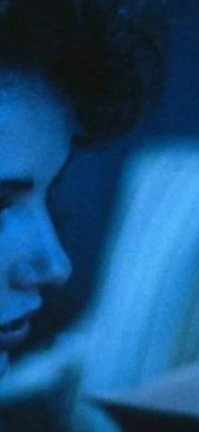 Still from The Fly showing a close-up of a man and a woman in blue light