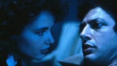 Still from The Fly showing a close-up of a man and a woman in blue light