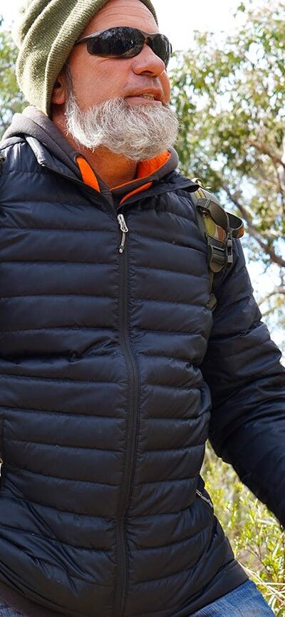First Nations man Tyronne Bell stands in a heavily grassed eucalyptus forest