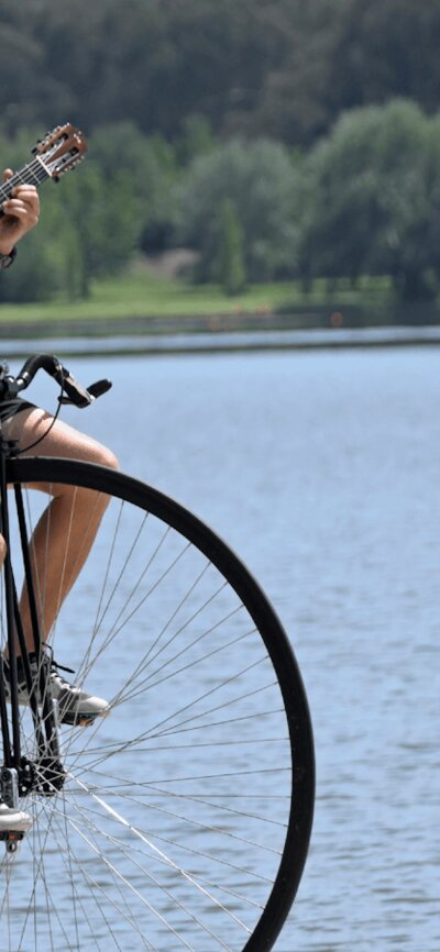 Simon playing a guitar while riding his penny-farthing