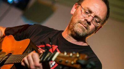David Rovics playing a guitar in front of a microphone