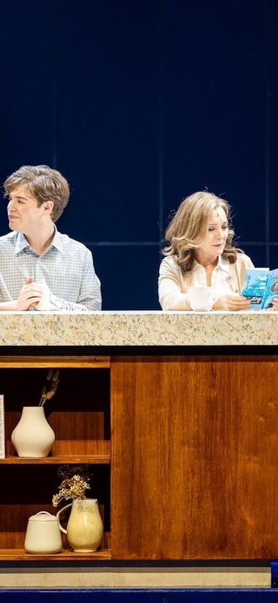 A group of people gather at a kitchen bench.