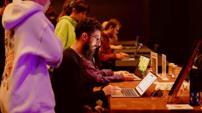 Pizza and Pixels Event 2026 A man with a beard sits at a laptop playing a game