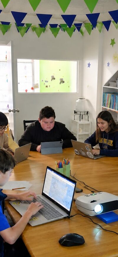 children sitting around a table and coding their apps