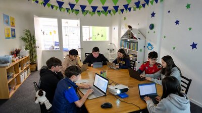 children sitting around a table and coding their apps