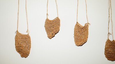 Dillybags by Jessika Spencer Five woven mesh dillybags hang on a white wall.