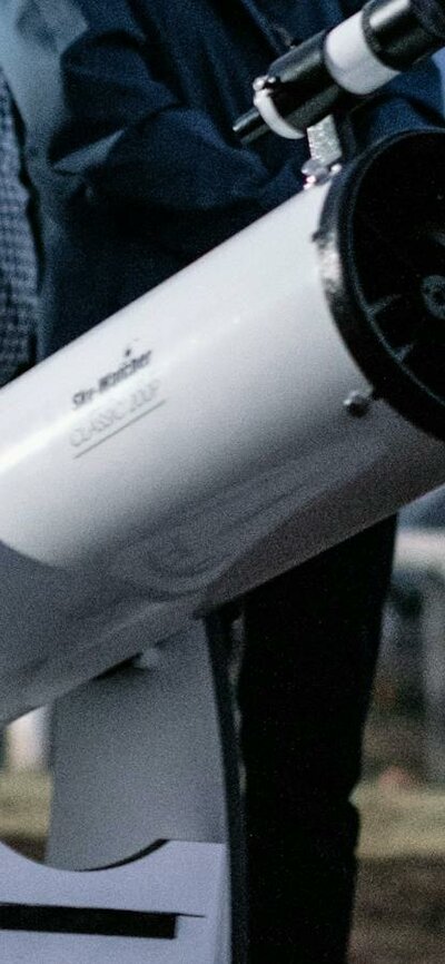Man puts his eye to telescope to study the sky