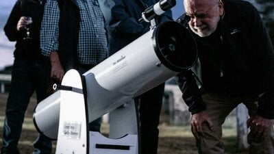 Man puts his eye to telescope to study the sky
