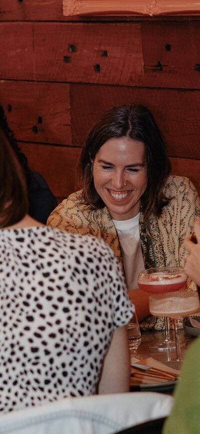 A group of younger women looking at question card smiling over a meal