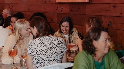 A group of younger women looking at question card smiling over a meal