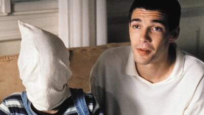 Double Feature: Run Lola Run + Funny Games Man wearing a white polo next to a figure with a white pillowcase on their head