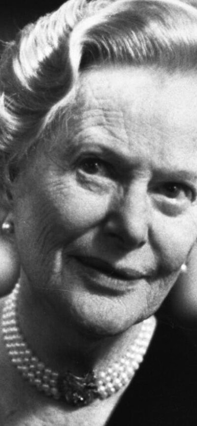 Older woman wearing pearls around neck looking past camera, black and white photo