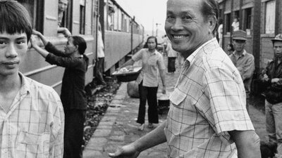 One older man with big smile turning back to look at camera, younger male on left looking at camera
