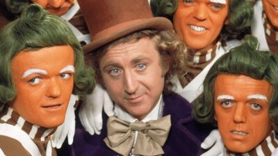 Man with top hat surrounded by small orange faced men