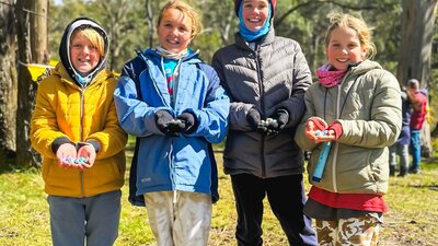 Four kids smiling at the camera as they show off the Easter eggs they found
