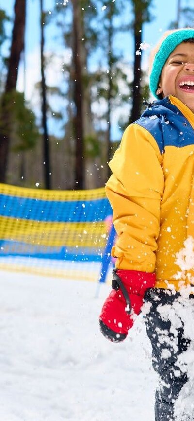 Father and son playing in the snow. Snow is sparaying around them as they laugh.