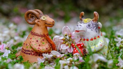 Elena Bozhko-Marshall - Goat and Cow Whistles Two ceramic figures, a goat and a cow in a field of flowers
