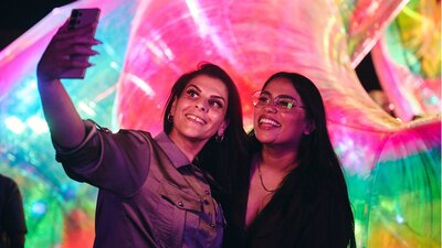 Two females capturing a selfie in front of an Enlighten installation