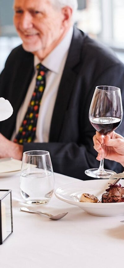 A woman seated at a table holding a glass of red wine.
