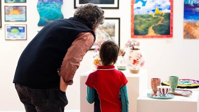 Installation View of Step Into The Limelight, 2024. A man and a boy looking at sculptures on a plinth