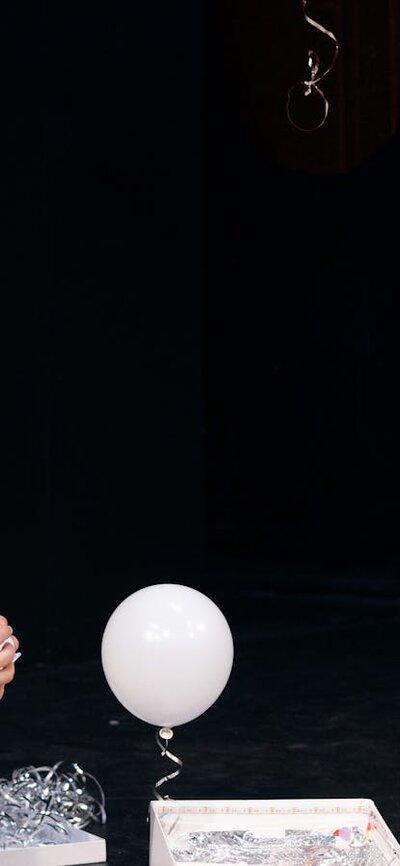 Man and woman with birthday hats watching a balloon float  out of a gift box