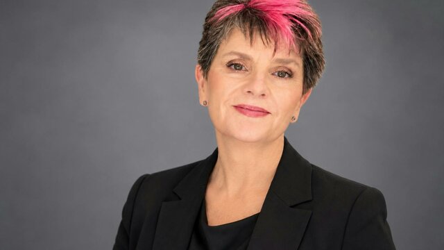 Karen Baldwin, Evidential Medium, brings live, unedited mediumship to Canberra and regional NSW. Portrait of Karen Baldwin, a woman with short dark hair with pink highlights, smiling and wearing a