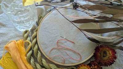 Art workshop samples. An embroidery hoop and thread next to a gin and tonic