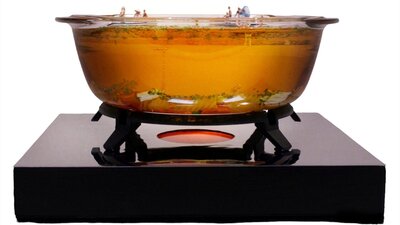 Glass bowl filled with amber coloured resin with miniature people inside