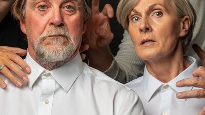 Two people, with crowns, surrounded by hands
