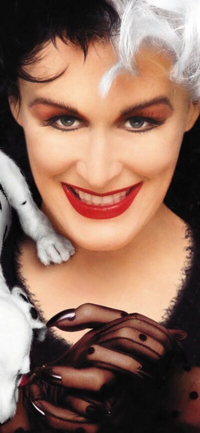 Woman with half black and half white hair with threedalmatian  puppies climbing over her